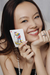 Young woman holding joker card