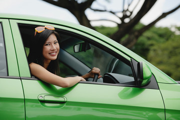 A young woman drives a green car