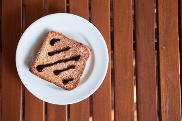 Fototapeta na wymiar Chocolate Spread on Toast in white disk on wood table