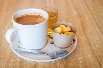 Coffee in white cup on disk with small cookies
