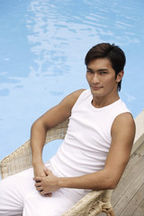 Young man sitting poolside