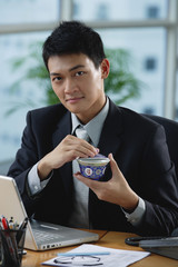 A man looks at the camera as he as he holds a Chinese tea cup