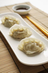 Fototapeta na wymiar 3 steamed gyoza dumplings placed on white plate with sauce on the side