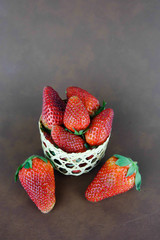  Fresh strawberries in a basket on brown background.