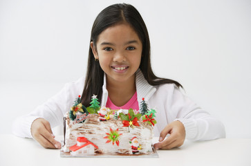 Girl with Christmas log cake smiling at camera