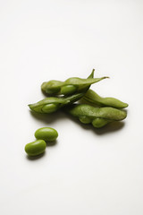multiple green edamame beans with pea pod broken