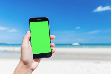 Beautiful woman's hand using smart phone at beach.