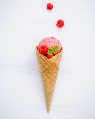 Raspberry ice cream in cone with fresh raspberry and peppermint