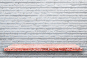 Empty top of pink granite stone table on white rough stone wall