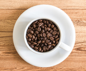 Top view shot of organic coffee bean in ceramic cup over ceramic tile.