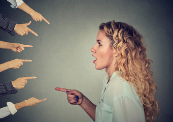 Side profile shocked girl pointing against many fingers