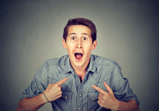 young happy surprised man pointing at himself you mean me