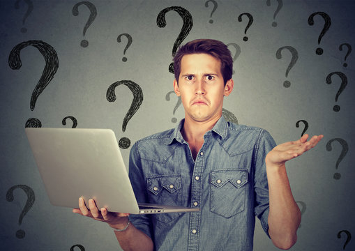 Perplexed young man with laptop many questions and no answer