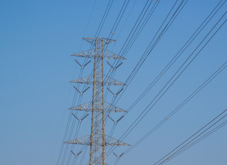 High voltage cable on electric tower with blue sky background..