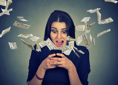 Surprised woman using smartphone dollar bills flying away from screen