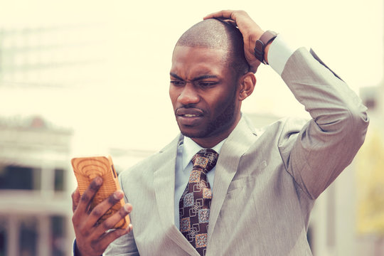 stressed man holding cellphone looking at screen with cross face expression