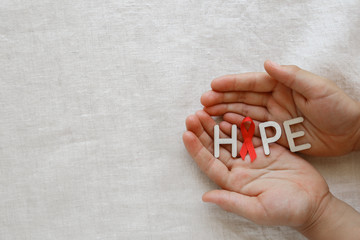 HOPE word with Red Ribbons on hands, toning copy space background, HIV/AIDS, Anosmia, Heart disease,Epidermolysis bullosa and Vasculitis awareness