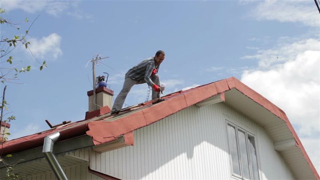 works man on Roof/man standing on the roof and the roof painted in red paint
