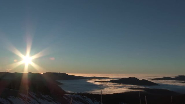 Sunrise time lapse over Pacific Northwest in Oregon on clear blue sky morning with fog rolling over mountainous landscape.