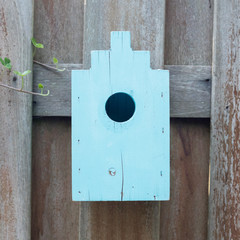 Blue birdhouse on a wooden fence