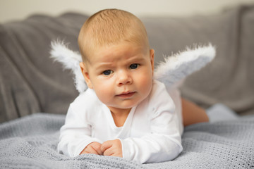 Baby laying on his stomach with angel wings attached