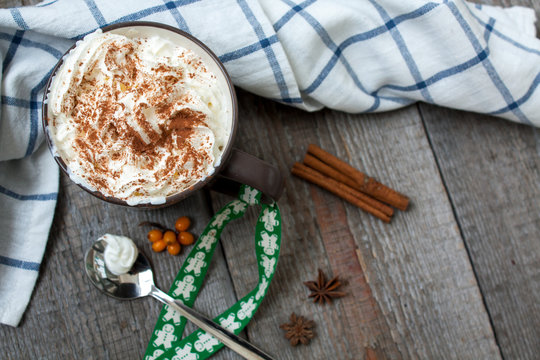 Christmas drink with whipped cream, decorated with a ribbon with a gingerbread man. hot chocolate or cocoa with chocolate, cinnamon, berries.
