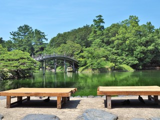 Obraz premium Wooden benches and wooden bridge - Engetsukyo in Ritsurin Garden in Takamatsu city, Kagawa Prefecture, Japan. Ritsurin Garden is one of the most famous historical gardens in Japan.