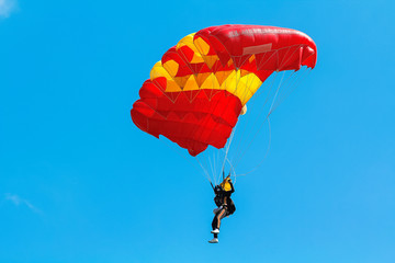 Skydiver and colorful parachute on blue sky background