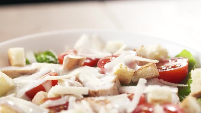 few grated parmesan chips falling onto caesar salad in slow motion