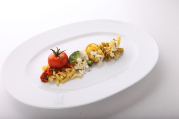 A prepared plate of spaghetti broccoli ready for serving garnished with tomatoes and basil