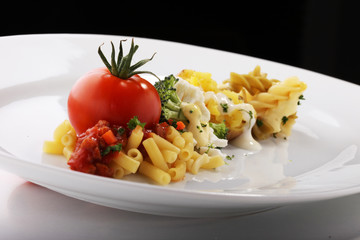 A prepared plate of spaghetti broccoli ready for serving garnished with tomatoes and basil