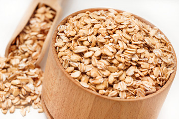 Close up of oatmeal in bowl and scoop on white background. Healthy food. Top view, high resolution product