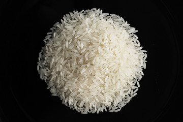 a pile of uncooked rice against a black plate