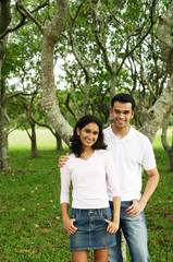 Couple standing in park, looking at camera