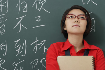woman looking up in front of chinese characters written in chalk