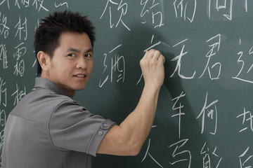 man writing Chinese characters on chalk board