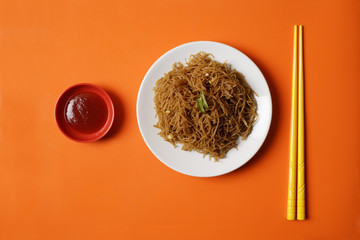 Noodles on plate with chopsticks.