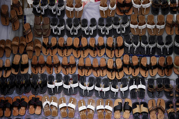 Many leather sandals on display at market.