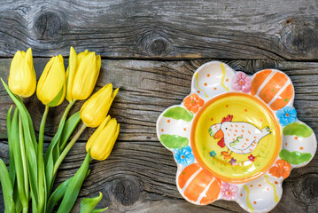 Fresh yellow tulip flowers with towel on ancient vintage wooden table  plates.