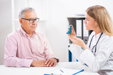 Doctor is telling to her patient how to use inhaler.