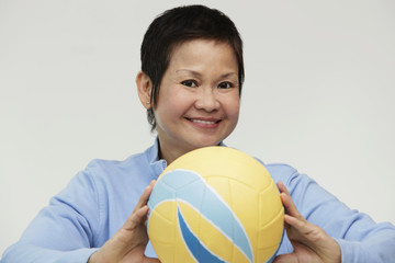 Mature woman holding a volleyball and smiling