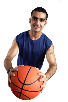 Young man holding basketball forward, looking at camera