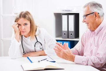 Doctor is getting bored while hypochondriac patient is explaining his health problems.