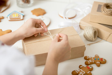 Close up of confectioner hands wrapping a simple kraft cardboard box. Christmas concept photo, lifestyle