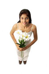 Woman standing with flowers, looking at camera
