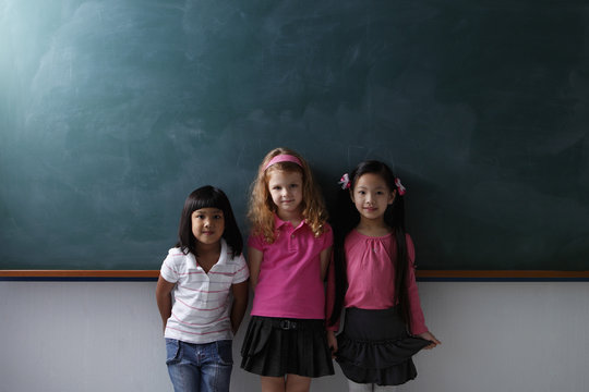 three young girls standing in front of chalk board