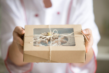 Hands holding out craft box with the most amazing collection of decorated Christmas cookies. Close...