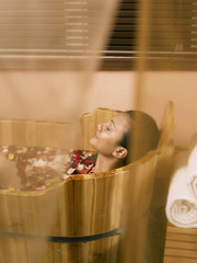 Fototapeta na wymiar woman relaxing in wooden spa tub
