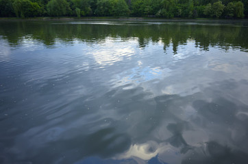 Abstract water surface with clouds reflected on the water and tr