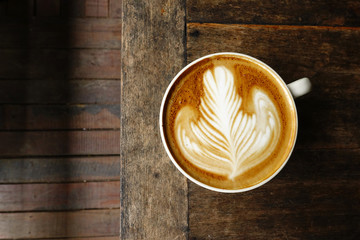 cup of latte art coffee on wooden background